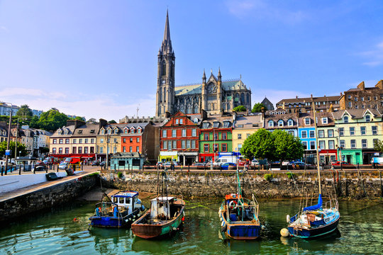 Colorful buildings and old boats with cathedral in background in the harbor of Cobh, County Cork, Ireland
