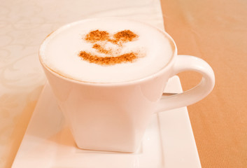 white Cup of cappuccino with a smile of cinnamon