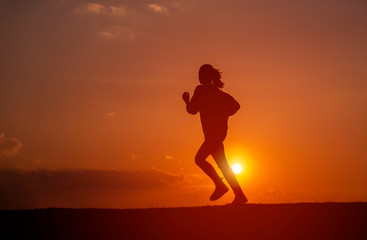 Silhouette of the running girl at sunrise.