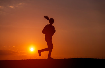 Silhouette of the running girl at sunrise.