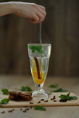 hand stirs hot steaming tea in glass. winter hot seasonal drinks
