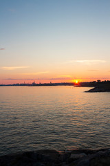 View of the Gulf of Finland at sunset of a summer day from the steep rocky shore of the island Suomenlinna Sveaborg in Finland. View from the island towards Helsinki on the horizon.