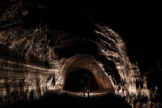 A male caver holding a propane lantern while exploring the 13,042 foot long Ape Cave near Mount St. Helens in the Gifford Pinchot National Forest of western Washington State. The cave is the third longest known lava tube in North America. The cave is open year round and has a easier, shorter lower cave section and a slightly more physical and longer upper cave section.