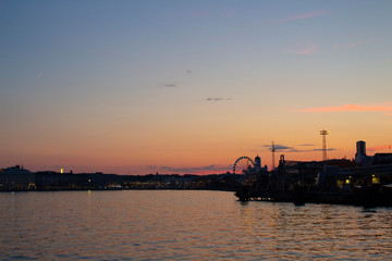 Fototapeta na wymiar View of the embankment of Helsinki, houses and the silhouette of the Cathedral of St. Nicholas from the Gulf of Finland at dusk on a bright summer night in the capital of Finland.