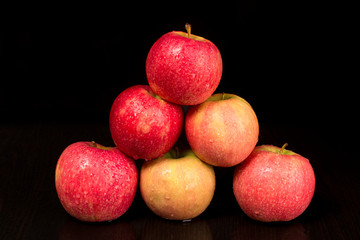 A few apples stacked slide, on a black background, water drops on apples