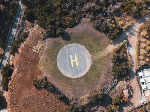 blue helicopter landing spot surrounded by green trees