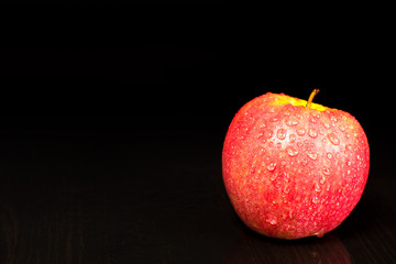 Red Apple in water drops on dark background, place for text