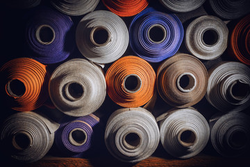 many textile rolls of blue, white and orange colors stacked one over the other in dark light