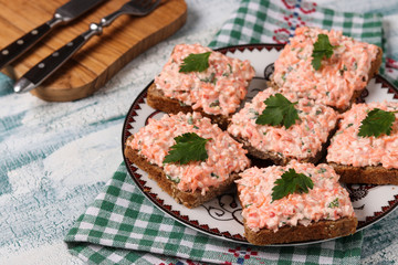 Sandwiches with crab sticks and carrots on a plate on a blue background