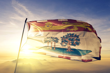 Prince Edward Island province of Canada flag waving on the top sunrise mist fog