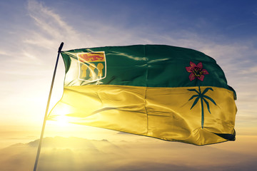 Saskatchewan province of Canada flag waving on the top sunrise mist fog - obrazy, fototapety, plakaty