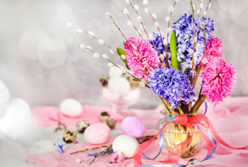 Easter eggs with beautiful hyacinths and willow bouquet on light background, spring holiday concept
