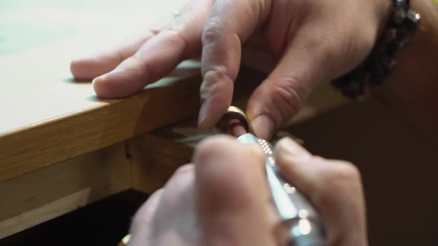 Jeweler makes a piece of jewelry - golden wedding ring