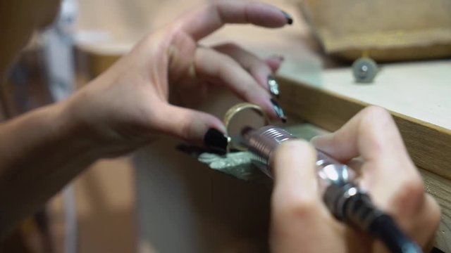 Jeweler makes a piece of jewelry - golden wedding ring
