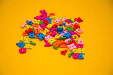 Fototapeta na wymiar Many multicolored wooden letters on a yellow background. toy letters. english alphabet. View from above. Flat lay. Copy space for text.