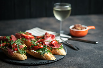 Traditional Italian bruschetta with dried tomatoes, prosciutto and arugula.