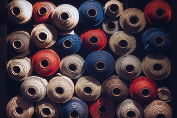 many textile rolls of blue, white and orange colors stacked one over the other in dark light - 254529536