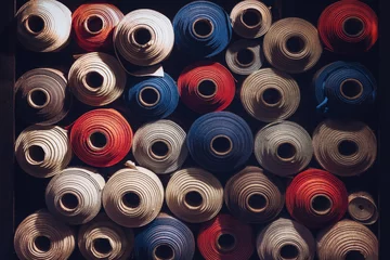 Fotobehang many textile rolls of blue, white and orange colors stacked one over the other in dark light © Alessandro Cristiano