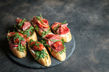 Traditional Italian bruschetta with dried tomatoes, prosciutto and arugula.