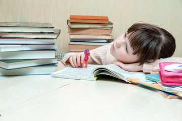 SThe schoolgirl laid her head on the book and thoughtfully looks into the distance. A child holds a...