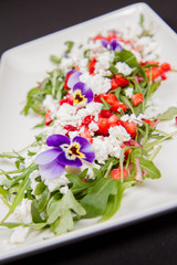 Salad made of cottage cheese, rocket salad, strawberries, pomegranates, onion decorated with flowers