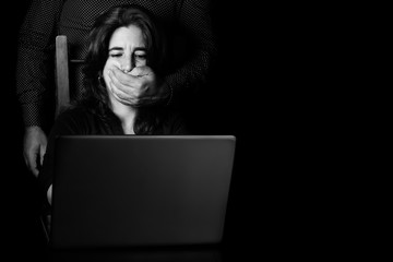 Woman typing on a computer with a hand covering her mouth - obrazy, fototapety, plakaty