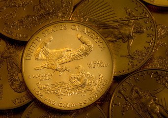 Pile of golden coins with Gold Eagle on US Treasury issue one ounce pure gold coin