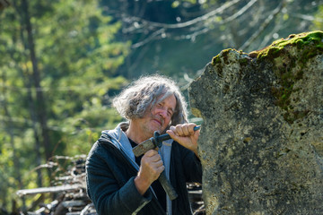 Senior sculptor with curly hair carving in stone