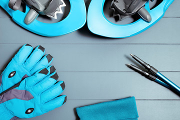 Flat top view on winter hiking equipment and gear such as snowshoes, trekking poles and blue gloves. Snow sports and recreation concept