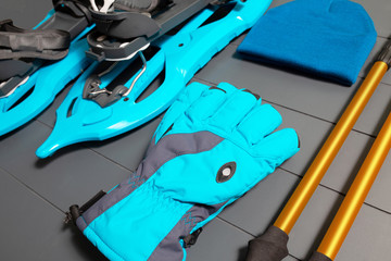 Winter sport and fitness recreation equipment. Trekking poles, snowshoes and clothes on wooden background