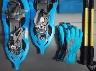 Winter sport and fitness recreation equipment. Trekking poles, snowshoes and clothes on wooden background