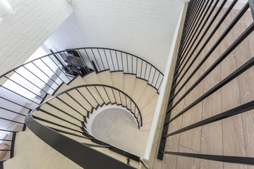 spiral staircase in bright interior with white brick wall in elite expensive apartment