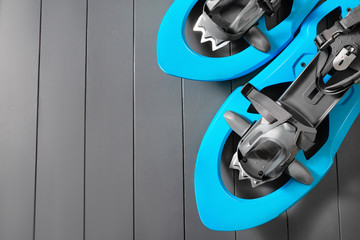 Colorful blue snowshoes studio shot on wooden background with copy space. Winter hiking equipment.