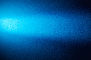 On the blue textural background a narrow light turquoise ray of light