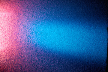 Bright pink glow and turquoise ray of light on a blue textural background