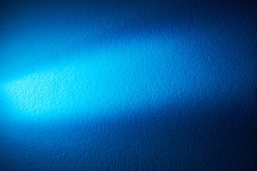 A wide light blue ray of light shines on the diagonal on a blue background