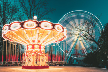 Illuminated Attraction Ferris Wheel And Carousel Merry-go-round On Summer Evening In City Amusement...