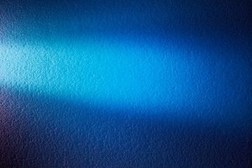 Bright light blue ray of light on a textural background of blue