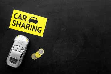 Carsharing concept, carsharing sign. Economical, chip trip. Toy car near coins on black background...
