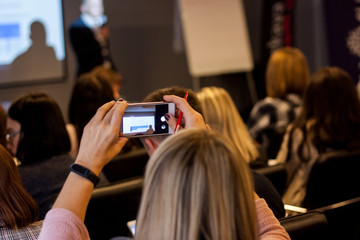 Woman taking picture with her phone at the conference