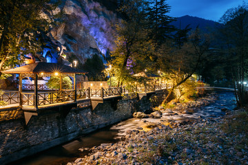 Borjomi, Samtskhe-Javakheti, Georgia. Night View Of Borjomula Mountain River Passing Through City, Park And Street Gazebo. Landscape Of Rocky River At Evening Night Illumination. Long Exposure