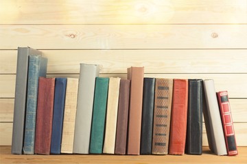 Ancient books in a row on wooden background