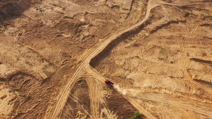 Aerial view of the large red truck moving on a sandy track in desert. Desert trip.