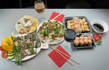 Fototapeta na wymiar A wonderful romantic dinner for two with Japanese rolls and glasses of red wine and white wine