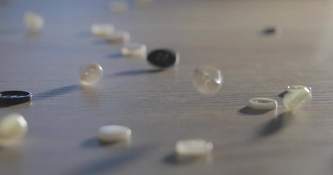 Slow motion video of the set of different buttons falls on a table