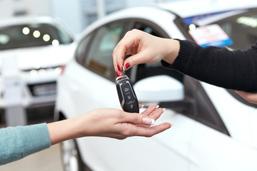 Here you go. Horizontal cropped hot of a car dealer passing keys to a new car female owner
