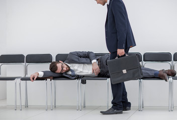 businessman walks past a sleeping visitor