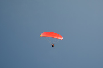 Red paradigler flying in a clear blue sky, Sirmione, Lombardy, Italy