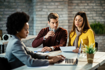 Couple going through paperwork while being on a meeting with financial advisor.