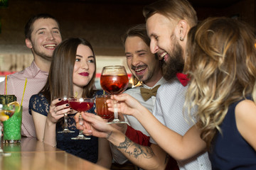 Loud celebration. Horizontal shot of attractive celebrating people laughing and smiling  holding cocktails in their hands.